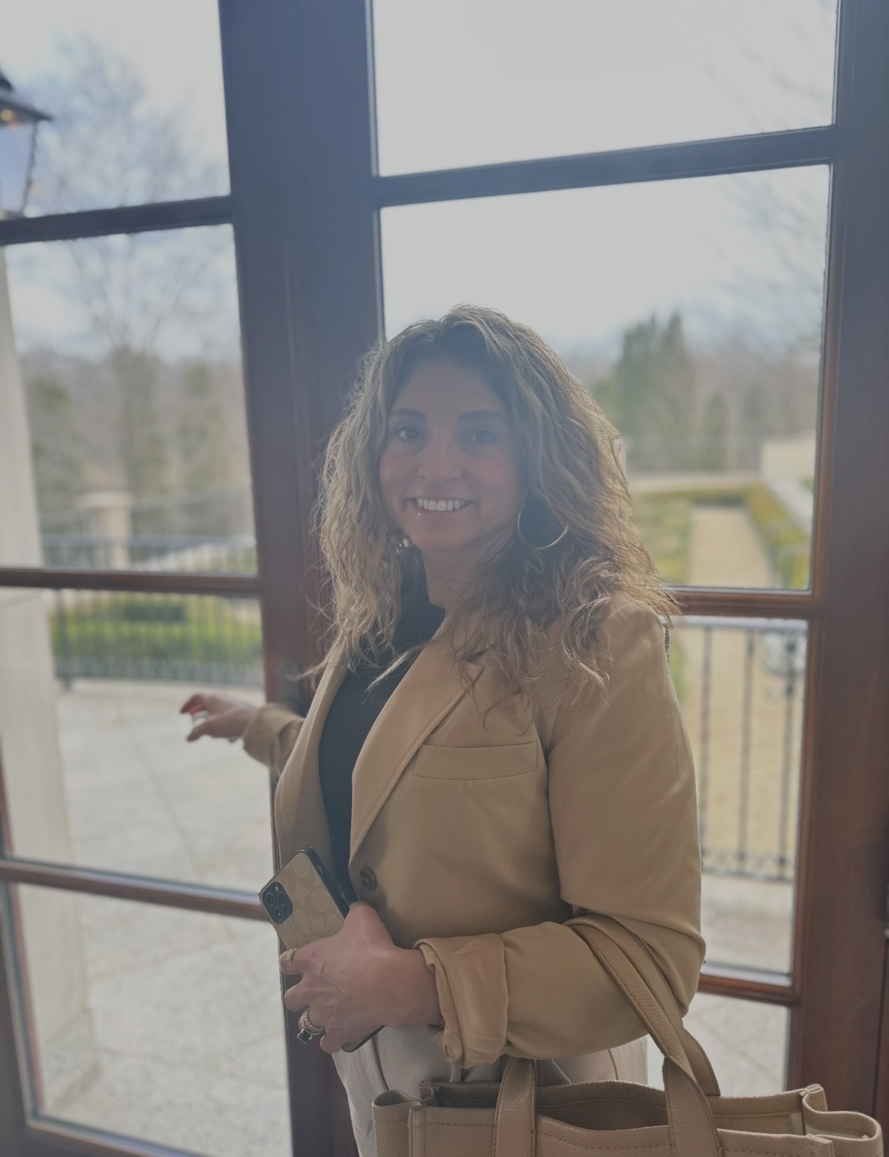 Nathalia, founder of HOME by Nathalia, smiling by tall French doors